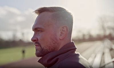A coach looking out over a running track at sunrise